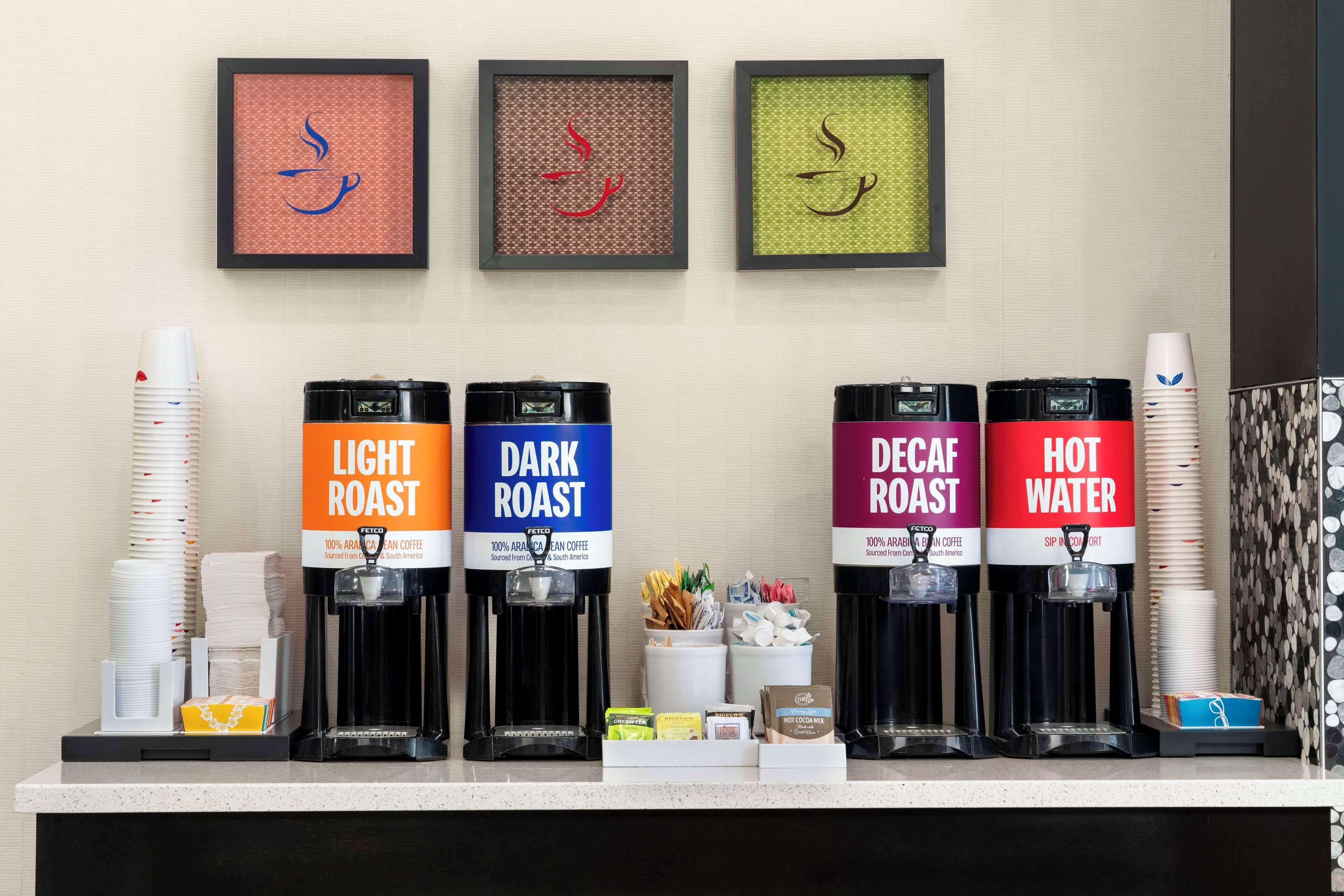 Un espace dédié au café, équipé de quatre distributeurs étiquetés « café léger », « café corsé », « café décaféiné » et « eau chaude ».