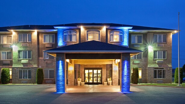 A multi-story hotel with a covered entrance, large windows, and a well-lit facade.