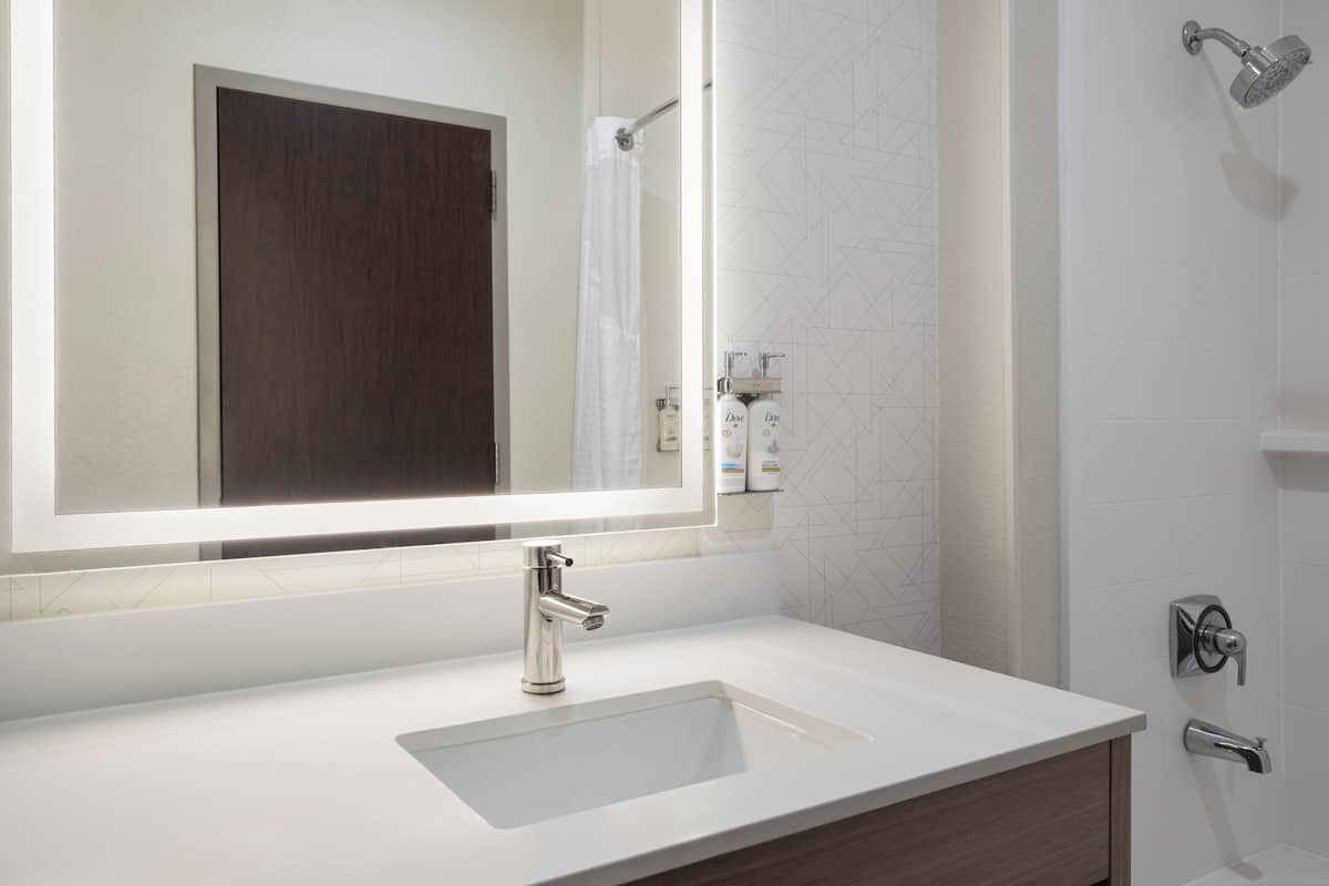 A bathroom with a white sink, a large mirror, and a shower.