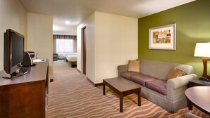 A hotel room with a sofa, a coffee table, a TV, and a framed picture on the wall.