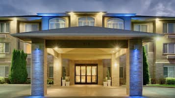 A hotel entrance with a covered walkway, large windows, and a number '712' above the doors.
