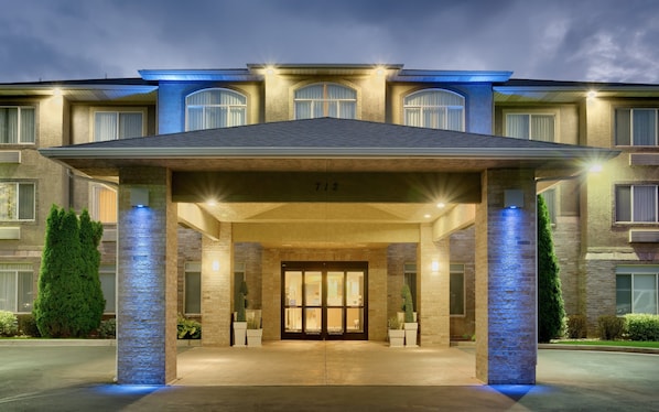 A hotel entrance with a covered walkway, large windows, and a number '712' above the doors.