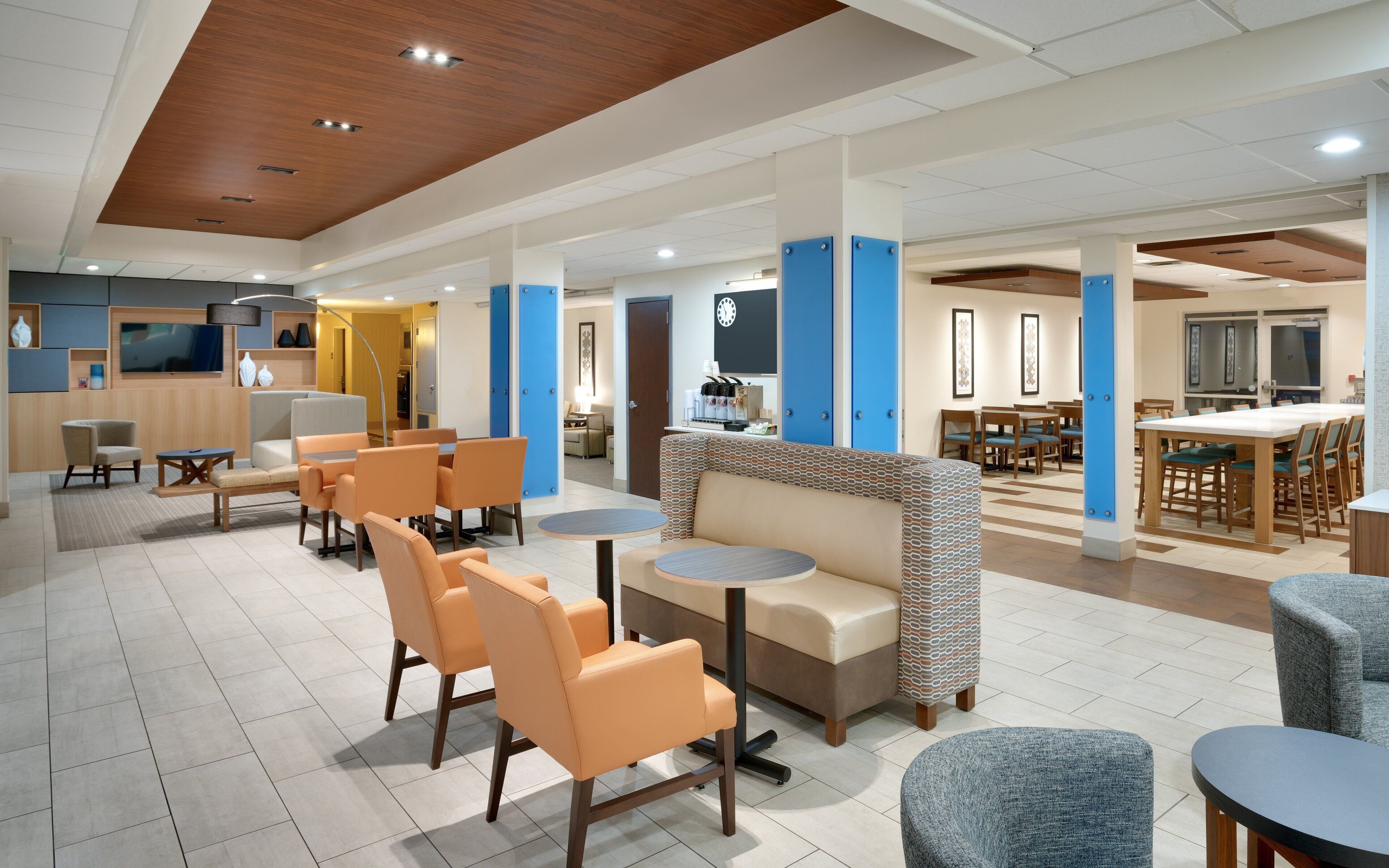 A hotel lobby with seating areas, a reception desk, and a dining area.