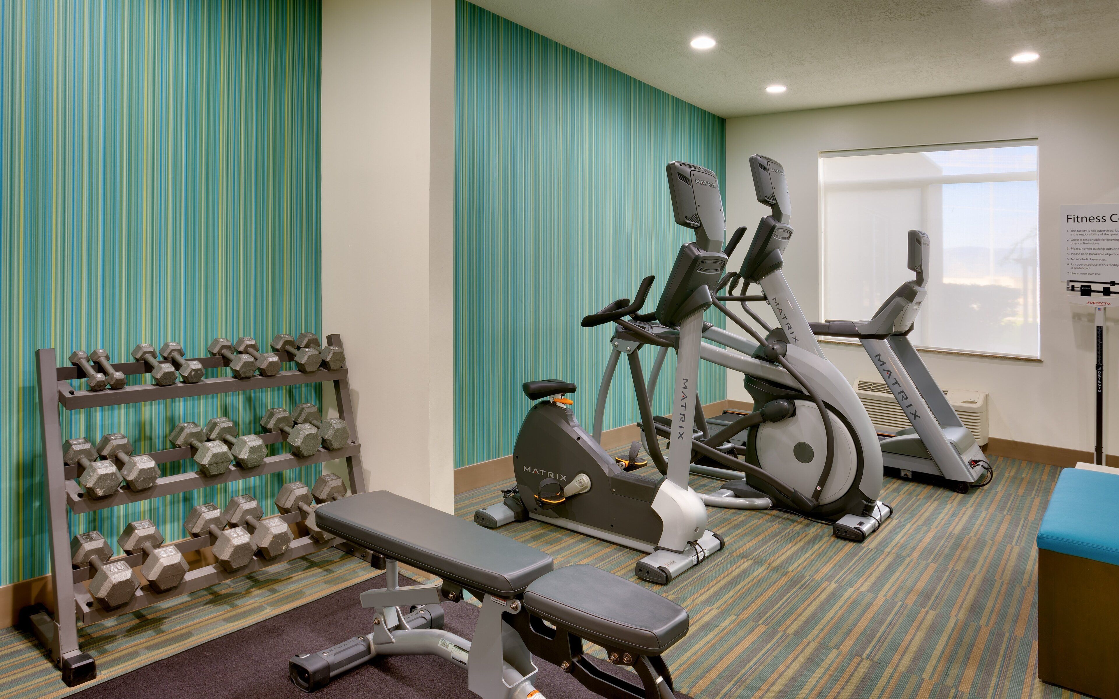 A fitness center with treadmills, a bench, and a rack of dumbbells.