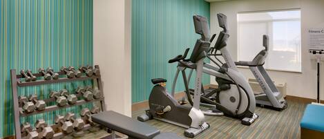 A fitness center with treadmills, a bench, and a rack of dumbbells.