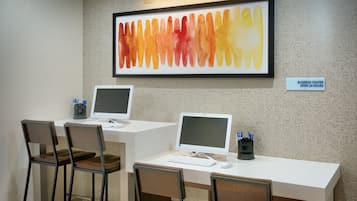 Un centro de negocios con dos escritorios, cada uno con computadora, teclado, ratón y portavasos.