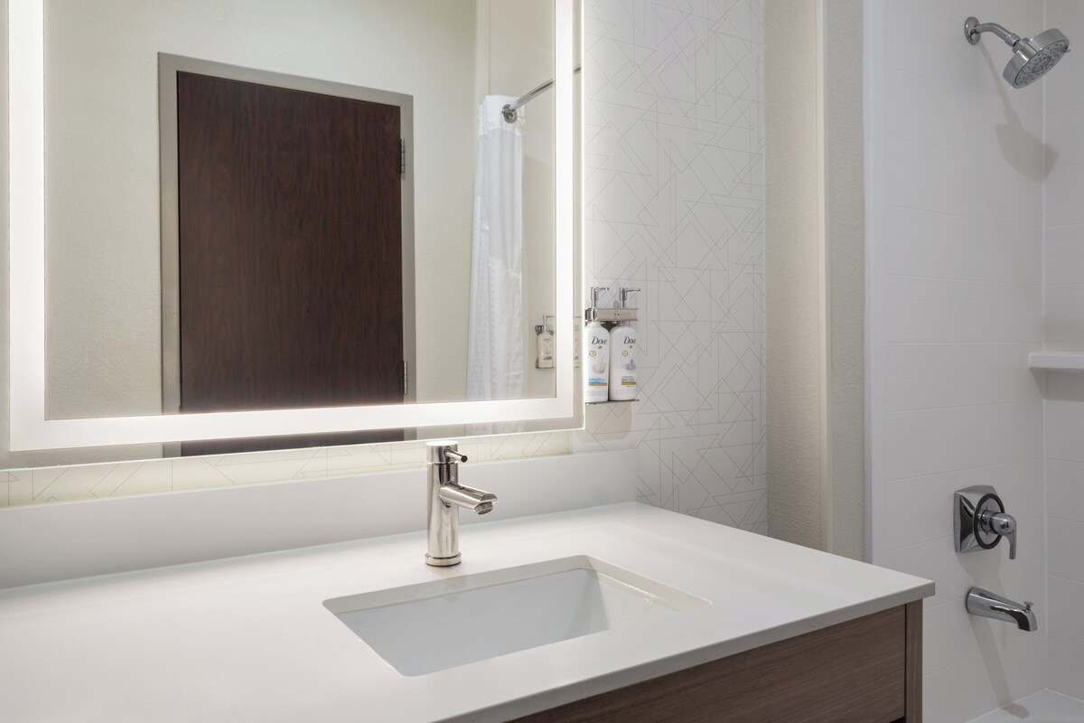 A bathroom with a white sink, a large mirror, and a shower.