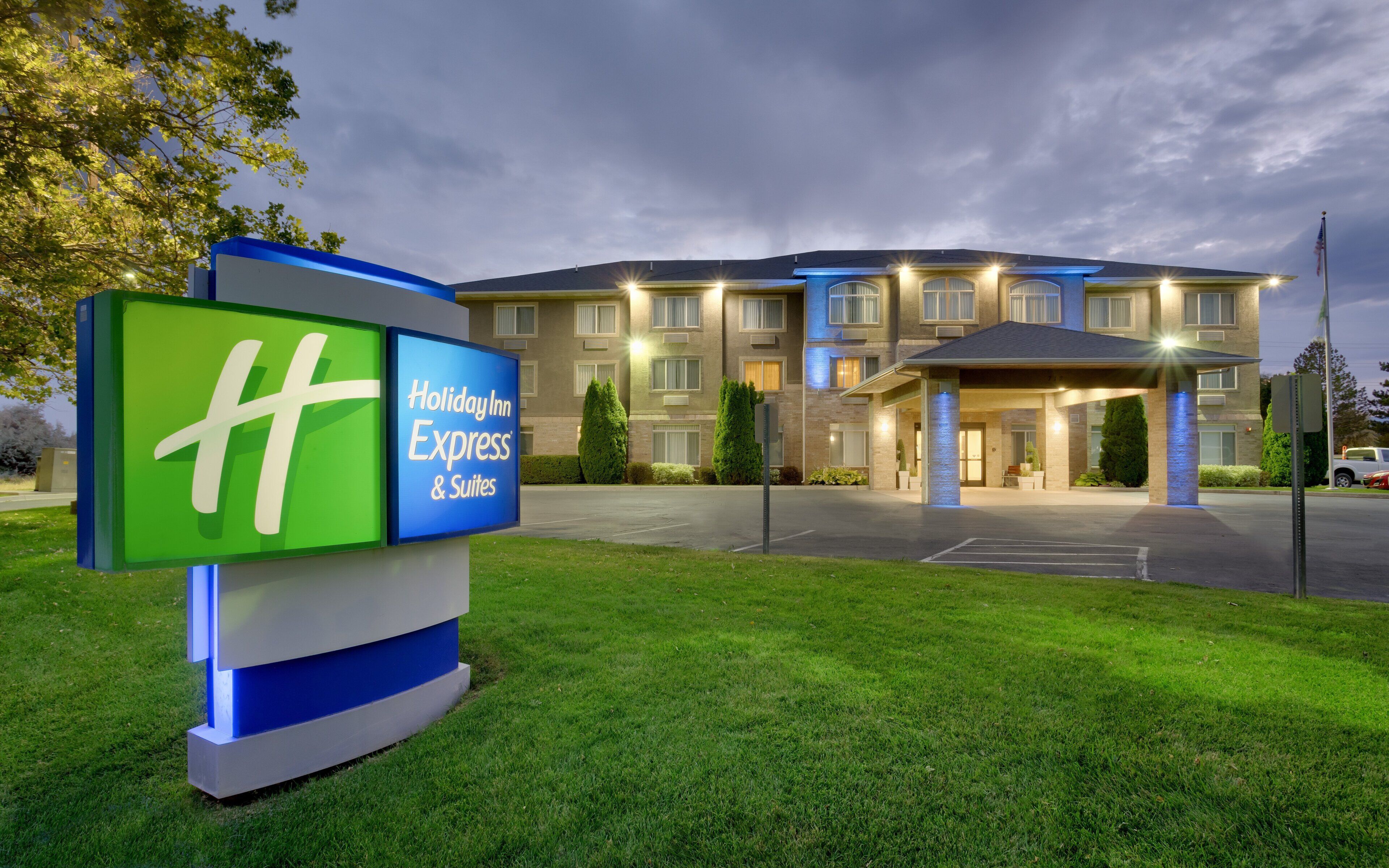 Ein Holiday Inn Express & Suites mit einer großen Schautafel, einem Parkplatz und einem Hauseingang.