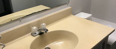 A bathroom with a beige sink, a mirror, and a white towel.