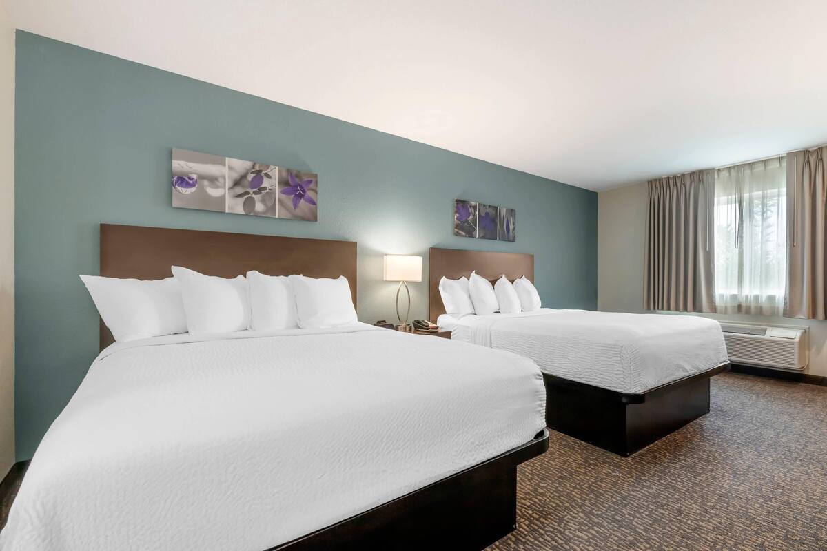 Une chambre d’hôtel avec deux lits, une table de chevet avec une lampe et des œuvres d’art accrochées au mur.