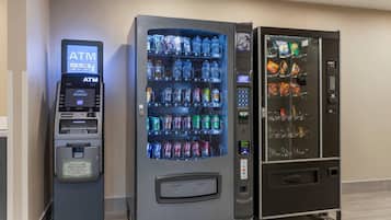 A row of vending machines including an ATM, a beverage dispenser, and a snack machine.