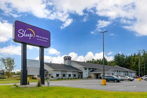 A Sleep Inn & Suites by Choice Hotels with a parking lot and a clear blue sky.