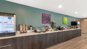 A reception area with a digital screen displaying a website, a coffee station, and a counter with various items.
