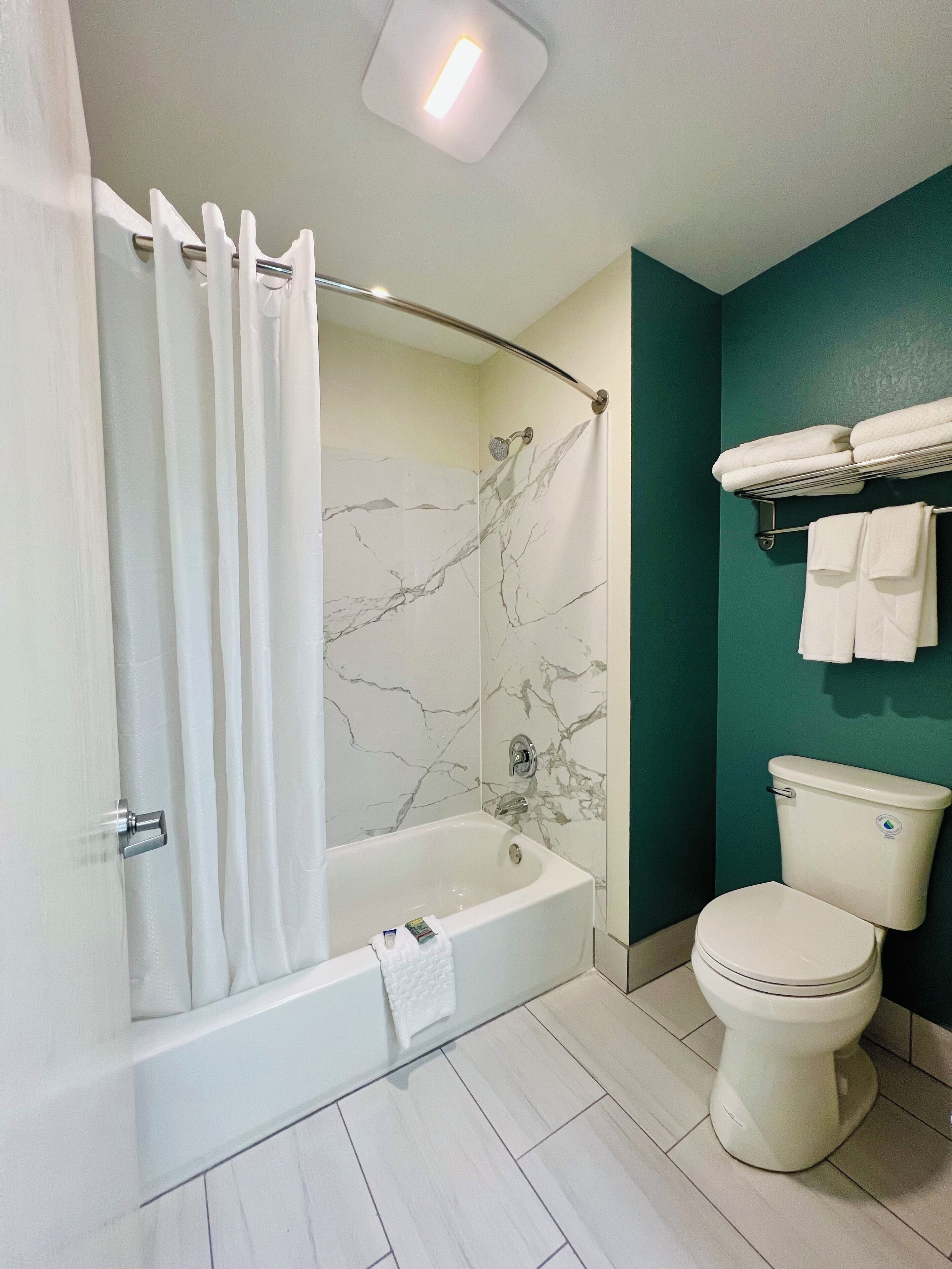 A bathroom with a bathtub, toilet, and a shower curtain.
