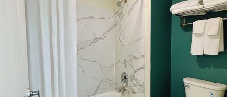 A bathroom with a bathtub, toilet, and a shower curtain.