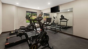 Un gimnasio con cintas de correr, bicicletas estáticas y equipo de ejercicio.