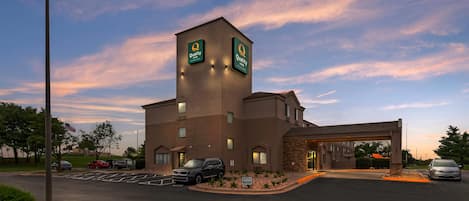 A hotel with a prominent tower, a parking lot, and a clear sky.