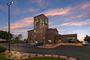 A hotel with a prominent tower, a parking lot, and a clear sky.