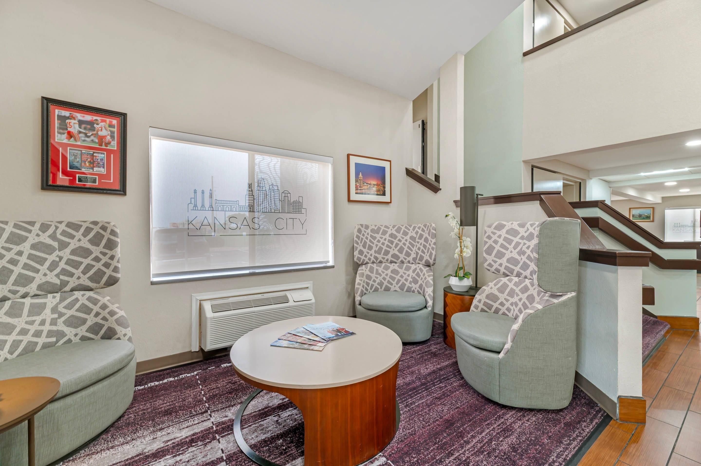 Un hall de hotel con una recepción, dos sillones, una mesita de centro y cuadros en las paredes.