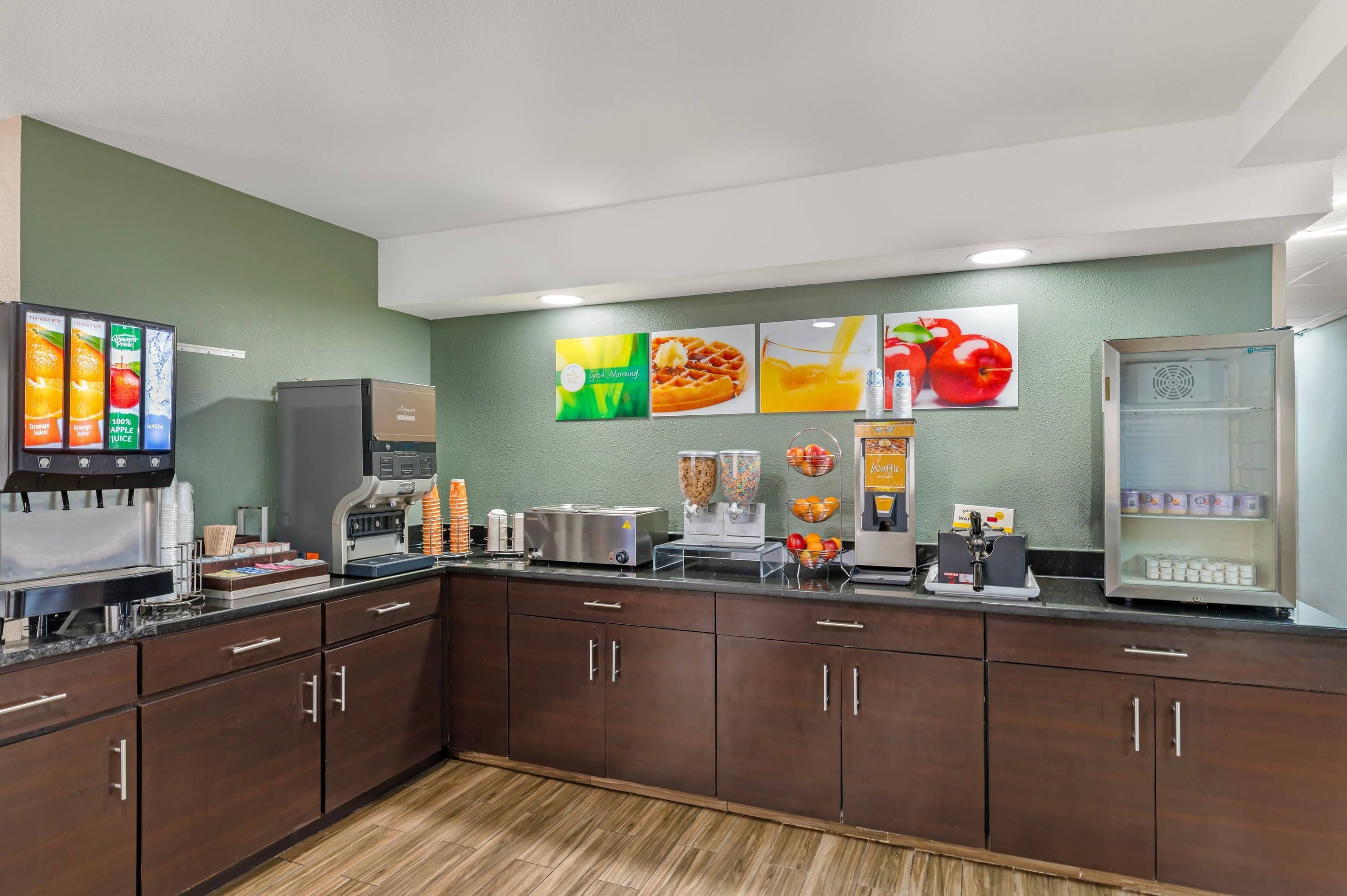 Una kitchenette con cafetera, máquina para waffles y diferentes dispensadores de alimentos.