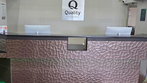A hotel reception desk with a textured wall design, a sign indicating 'Quality by Choice Hotels', and two computer monitors.
