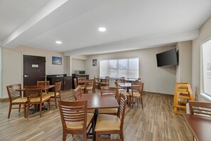 Un espace repas avec des tables et des chaises en bois, un coin cuisine équipé d’un four à micro-ondes et une vue sur la ville.
