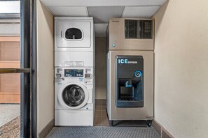 Un espace buanderie compact comprenant un lave-linge, un sèche-linge et un distributeur de glaçons.