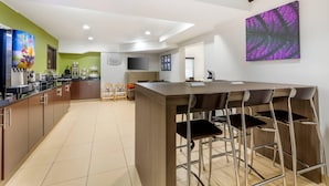 A modern kitchen with a bar area, wooden cabinets, and a large island with bar stools. - Sleep Inn at Greenville Convention Cente (Greenville)