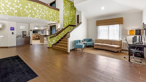 A spacious living area with a staircase, a sofa, a coffee table, and a desk with a chair. - Sleep Inn at Greenville Convention Cente (Greenville)