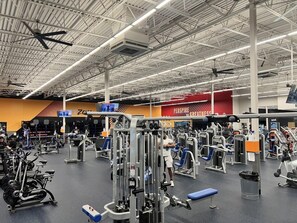 A gym with various exercise equipment, a high ceiling, and a visible brand name 'PERSPIRATE' on the wall. - Sleep Inn at Greenville Convention Cente (Greenville)