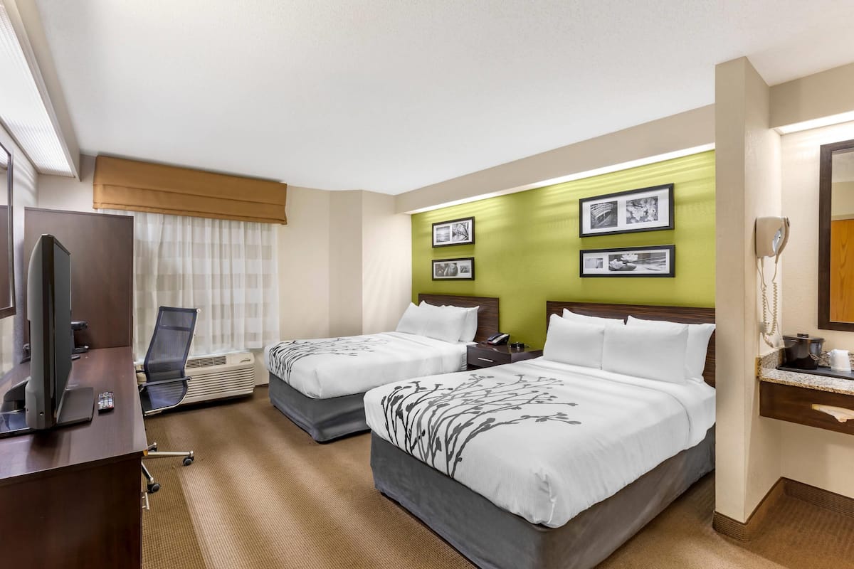 A hotel room with two beds, a desk with a computer, and a TV.