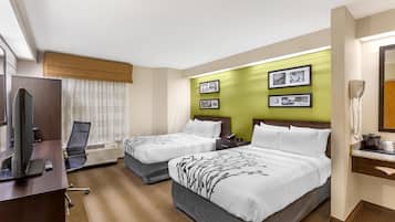A hotel room with two beds, a desk with a computer, and a TV.