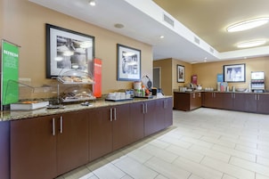 Un comedor de hotel con un bufé, que incluye una estación de café y diversas opciones de comida.