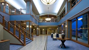 A spacious atrium with a central staircase, a chandelier, and a seating area with a large vase. - Bally’s Evansville Casino & Hotel (Evansville)