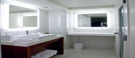 Un baño moderno con dos lavamanos, un espejo grande y una ducha a ras de suelo.