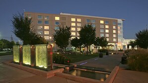 A hotel with a modern design, featuring a courtyard with a water feature and trees. - Bally’s Evansville Casino & Hotel (Evansville)