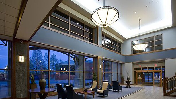 A spacious lobby with large windows, comfortable seating, and a modern chandelier. - Bally’s Evansville Casino & Hotel (Evansville)