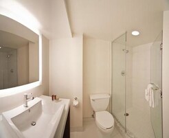 Un baño con un espejo grande, un lavabo, un inodoro y una ducha con mampara de vidrio.