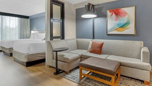 Une chambre d’hôtel avec un canapé, deux lits, une petite table et un tableau au mur.