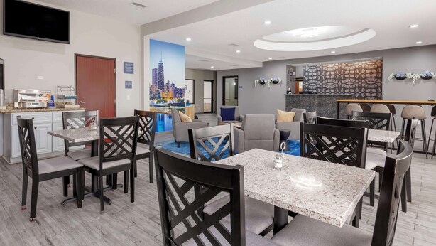 A modern hotel lobby with a seating area, a kitchen, and a cityscape mural.