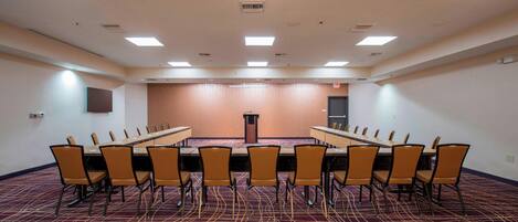 Una sala de conferencias con una larga mesa, varias sillas y un atril.