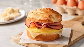 A breakfast sandwich on a wooden board.