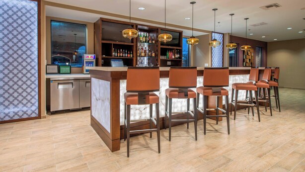 Un espace bar avec un comptoir, des tabourets de bar et des suspensions lumineuses.