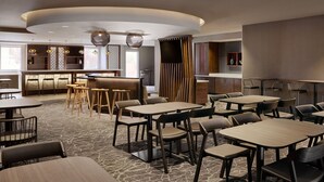 Un restaurant moderne avec des tables rondes, des places assises au bar et un espace bar central.