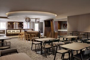 A modern restaurant with round tables, bar seating, and a central bar area.