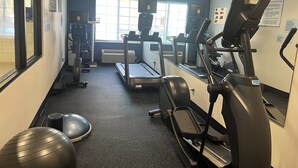 Une salle de sport équipée de tapis de course, de vélos elliptiques et de ballons d’exercice.