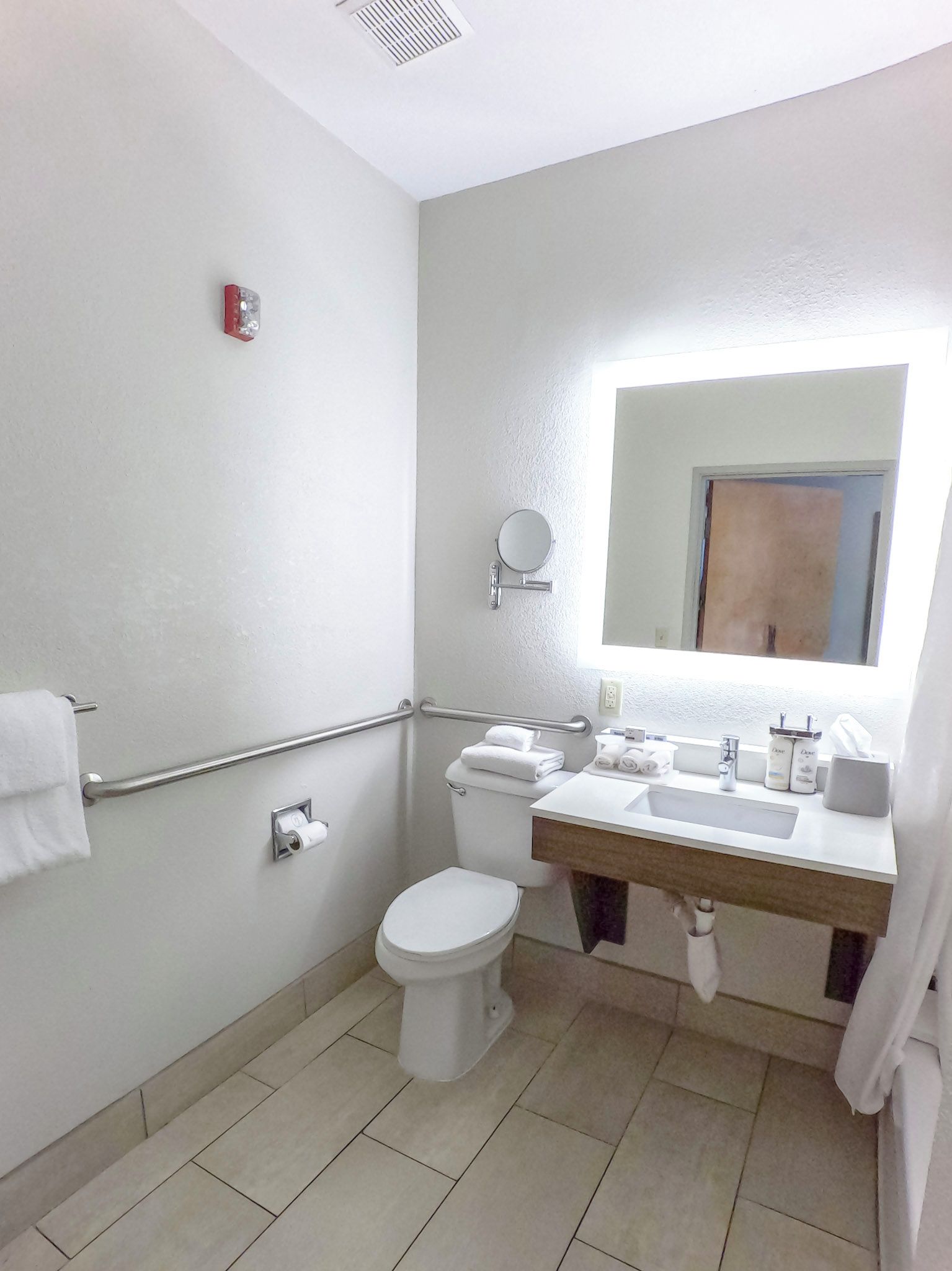 A bathroom with a toilet, sink, and mirror.