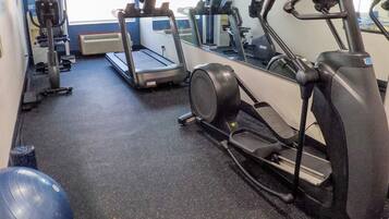 Un gimnasio con cintas de correr, elípticas y pelotas de ejercicio.