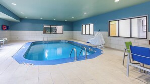 Une piscine intérieure avec des lignes de démarcation bien visibles, un vestiaire équipé d’un miroir et un espace détente avec des chaises.