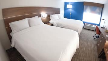 Ein Hotelzimmer mit zwei Betten, einem Schreibtisch, einem Stuhl und einem Fenster.